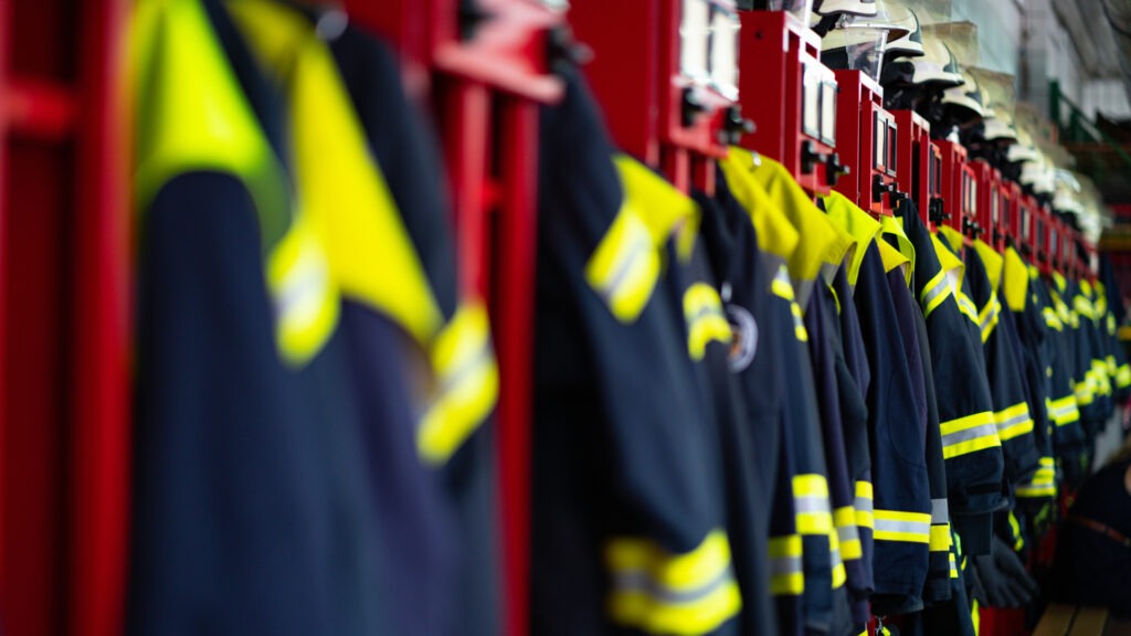 Brigada de Incêndio - Vestiário do corpo de bombeiros mostrando as roupas dos bombeiros e capacetes simbolizando a equipe que faz este trabalho